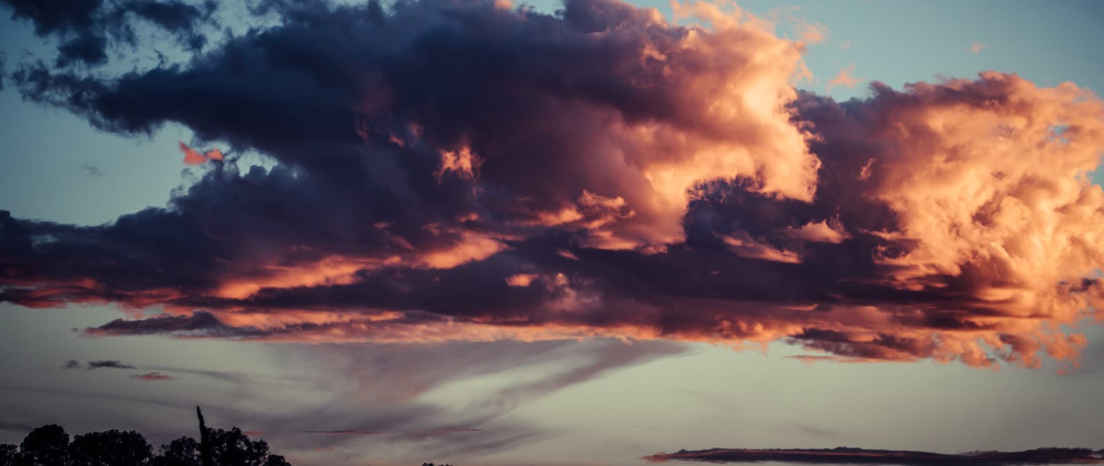 Wide atmospheric cloud band with dark navy depth and restrained gold edge light.